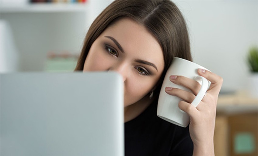 Kündigung - Frau sitzt mit Kaffeetasse vor Laptop